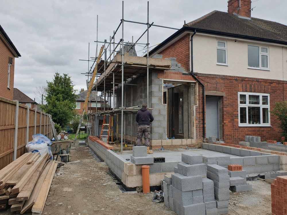 Single Storey Extension under construction with concrete block walls, scaffolding and worker