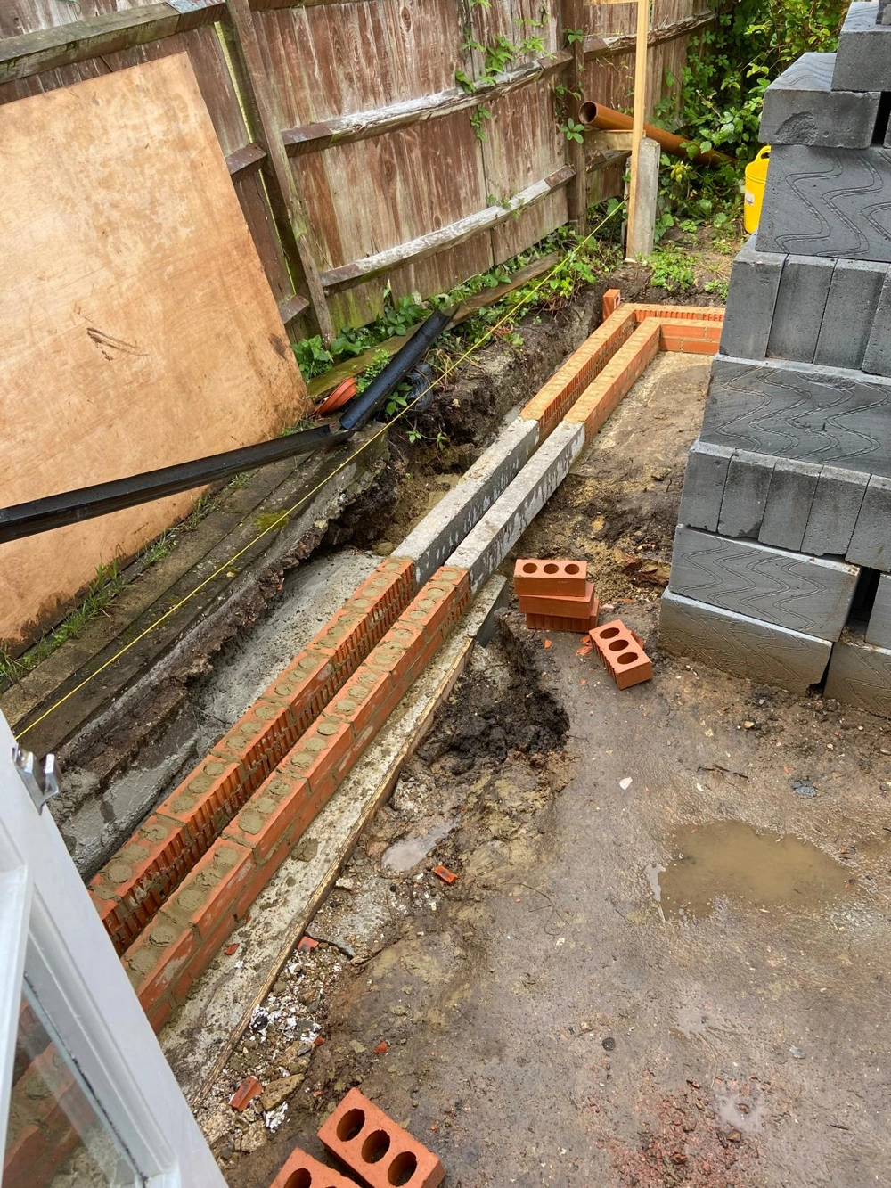 Bricklaying: two brick courses laid on new concrete foundation for single storey extension in a backyard