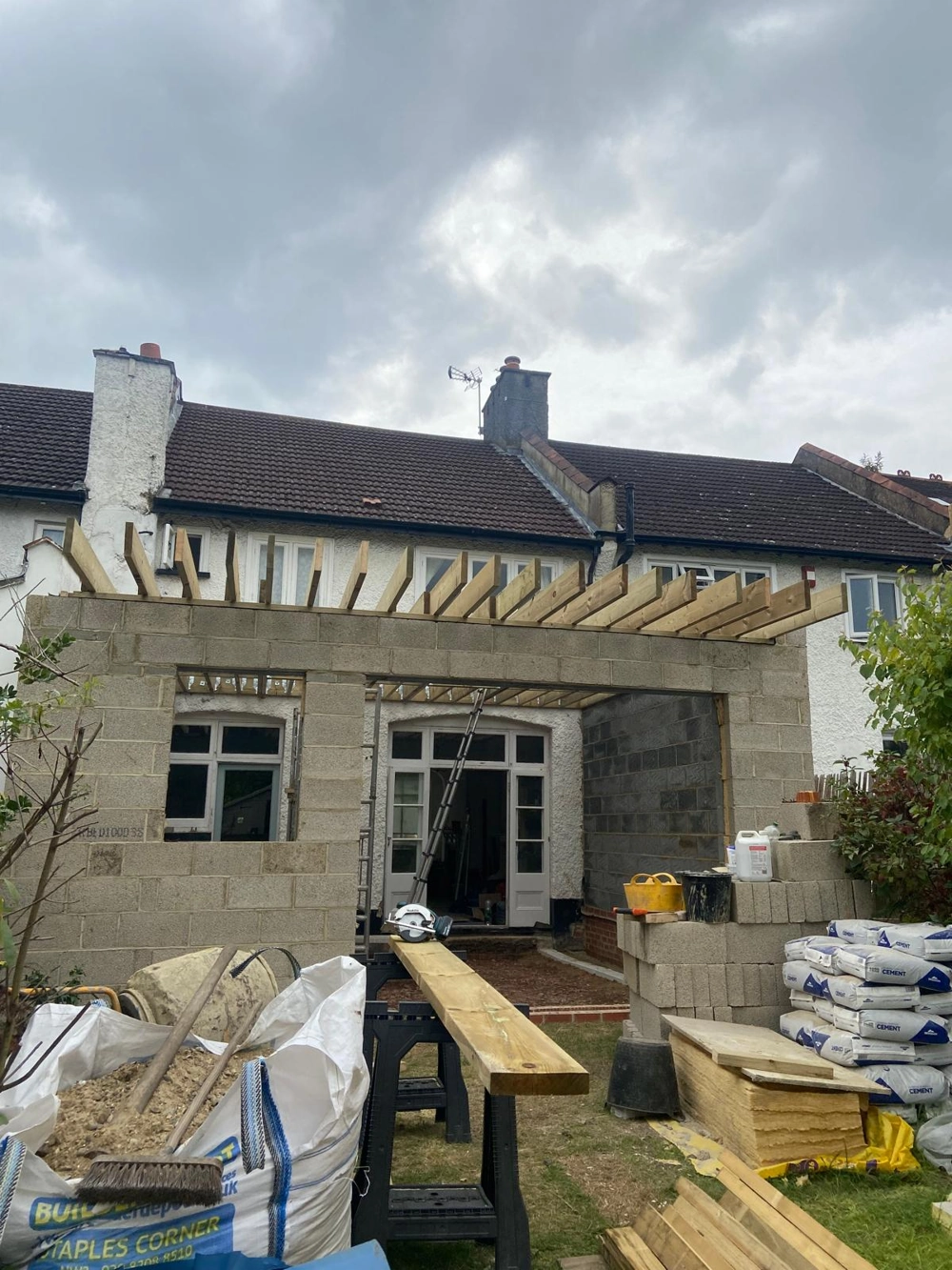 Rear Extension in progress: blockwork walls with exposed roof joists and construction materials in garden