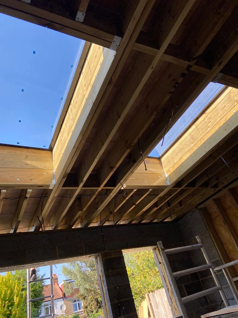 Interior view of loft extension under construction showing exposed wooden ceiling joists, skylight openings and blockwork walls