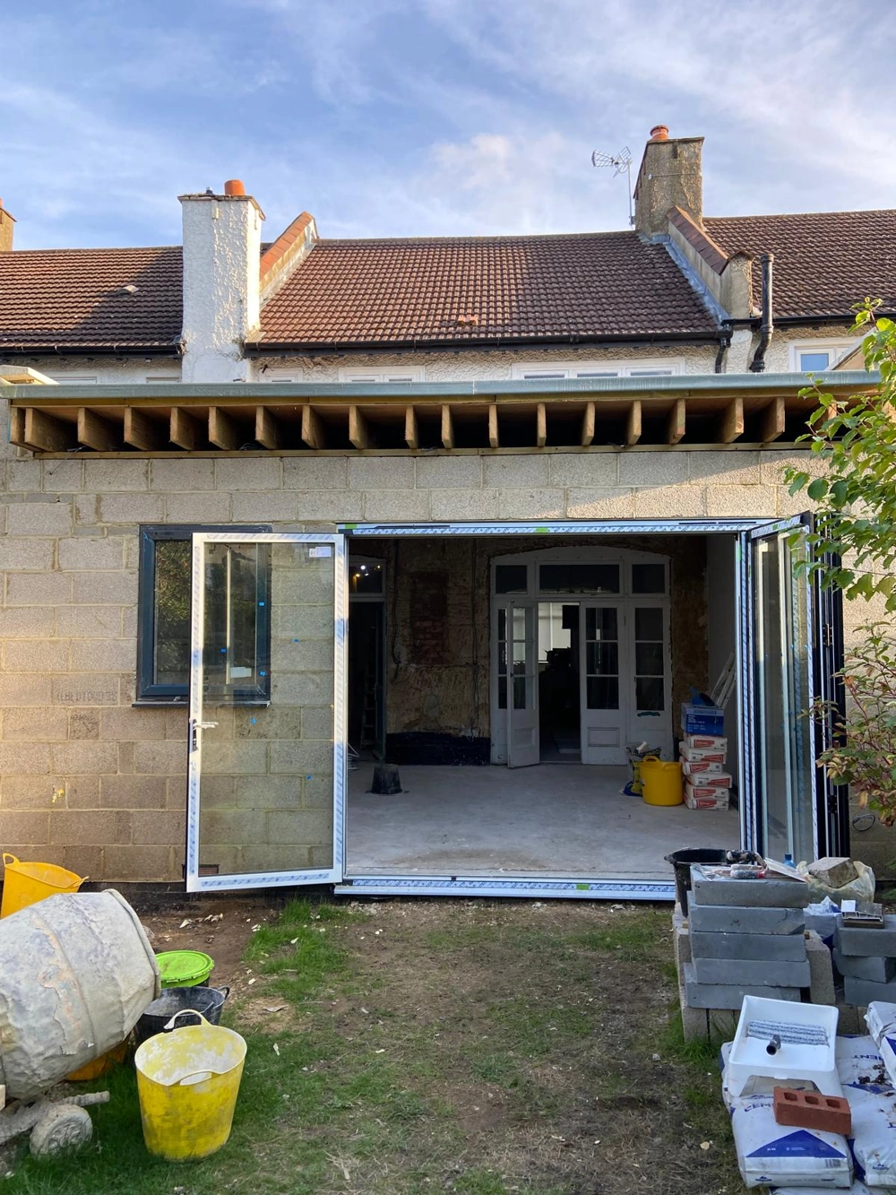 Under-construction rear extension with blockwork walls, exposed roof joists and bifold door frame