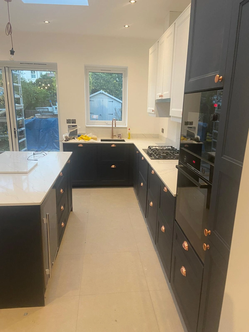 Modern kitchen with dark blue cabinets, white quartz countertops, central island, gas hob and integrated ovens – Kitchen Renovation