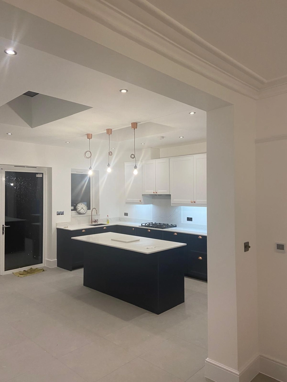 Modern open‐plan kitchen with black island, white cabinets and pendant lights – Kitchen Installation