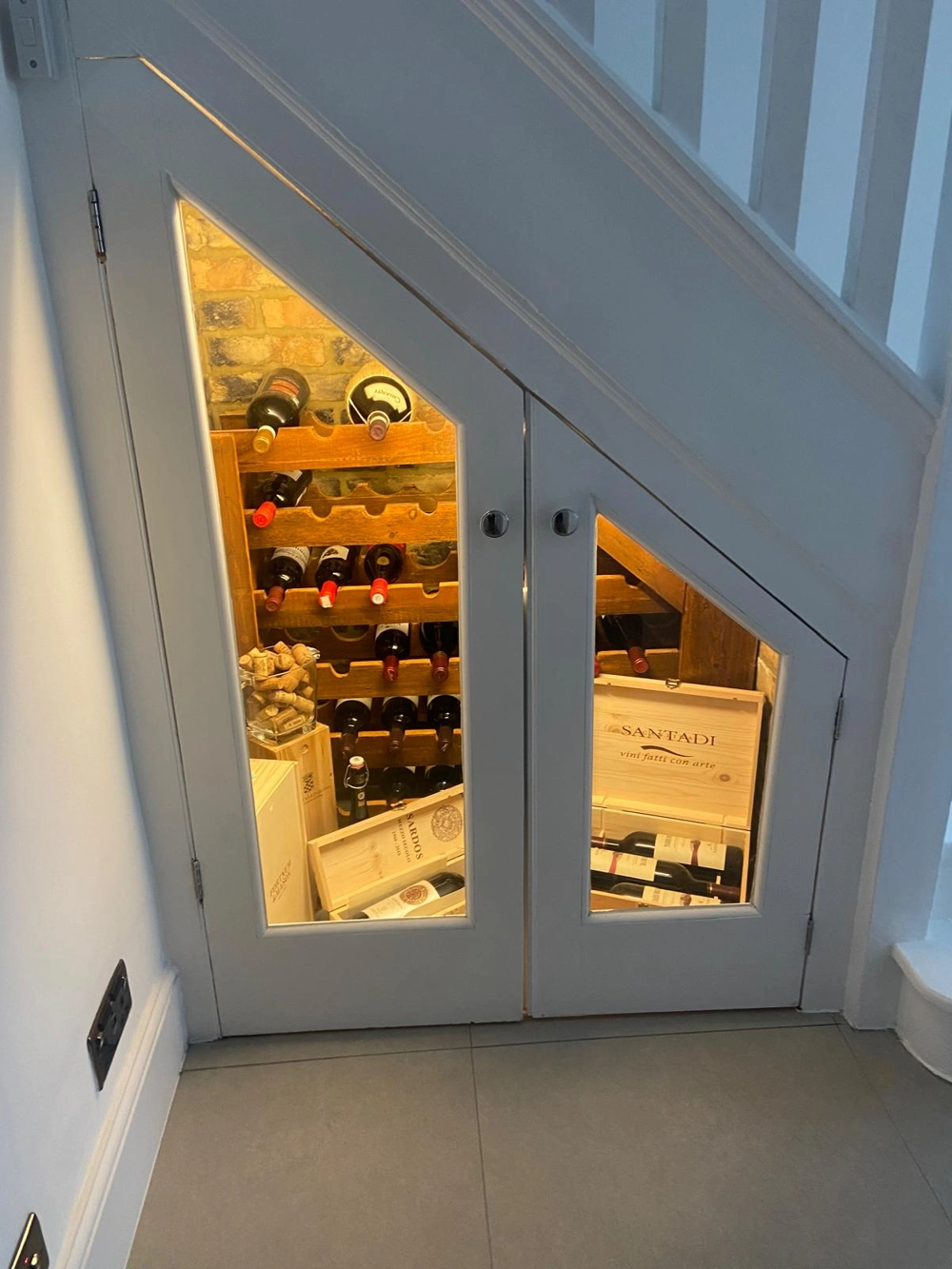 Under-stair bespoke furniture wine storage with wooden racks and warm LED lighting