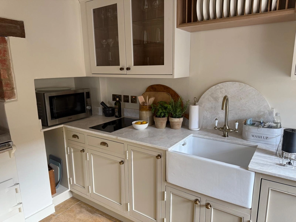 Shaker-style Kitchen Fitting with marble worktop, farmhouse sink, fitted cabinets and potted herbs