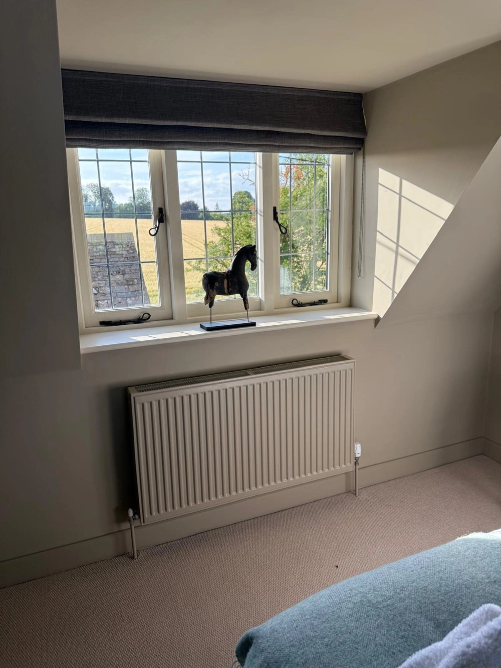 Carpeted loft bedroom with dormer window, radiator and decorative horse sculpture – Dormer Loft Conversion
