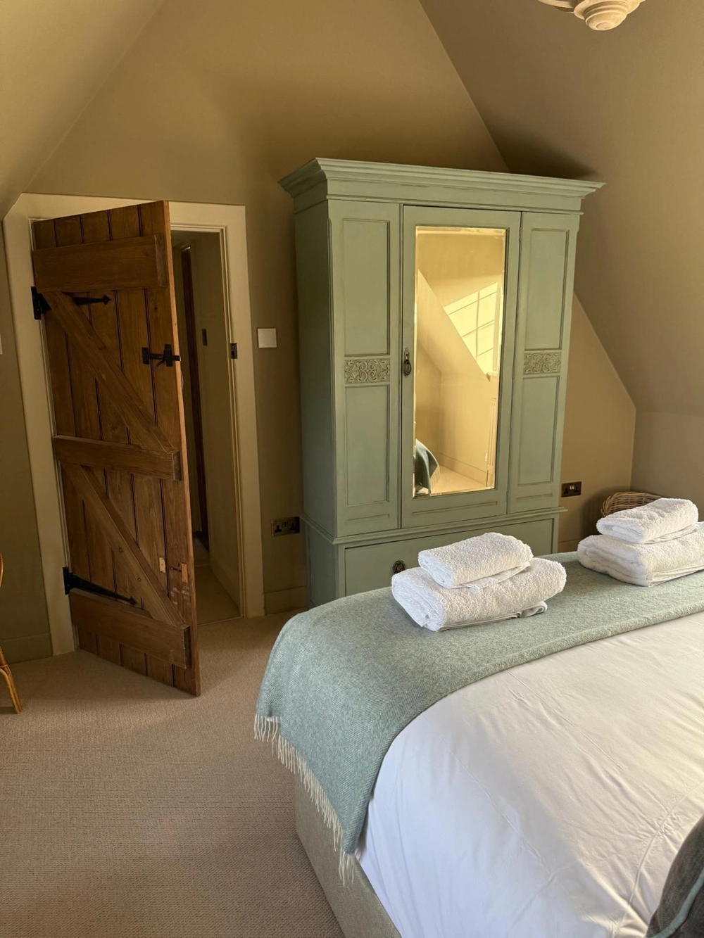 Attic Conversion with fitted painted wardrobe and barn door in cosy loft bedroom with linens and folded towels