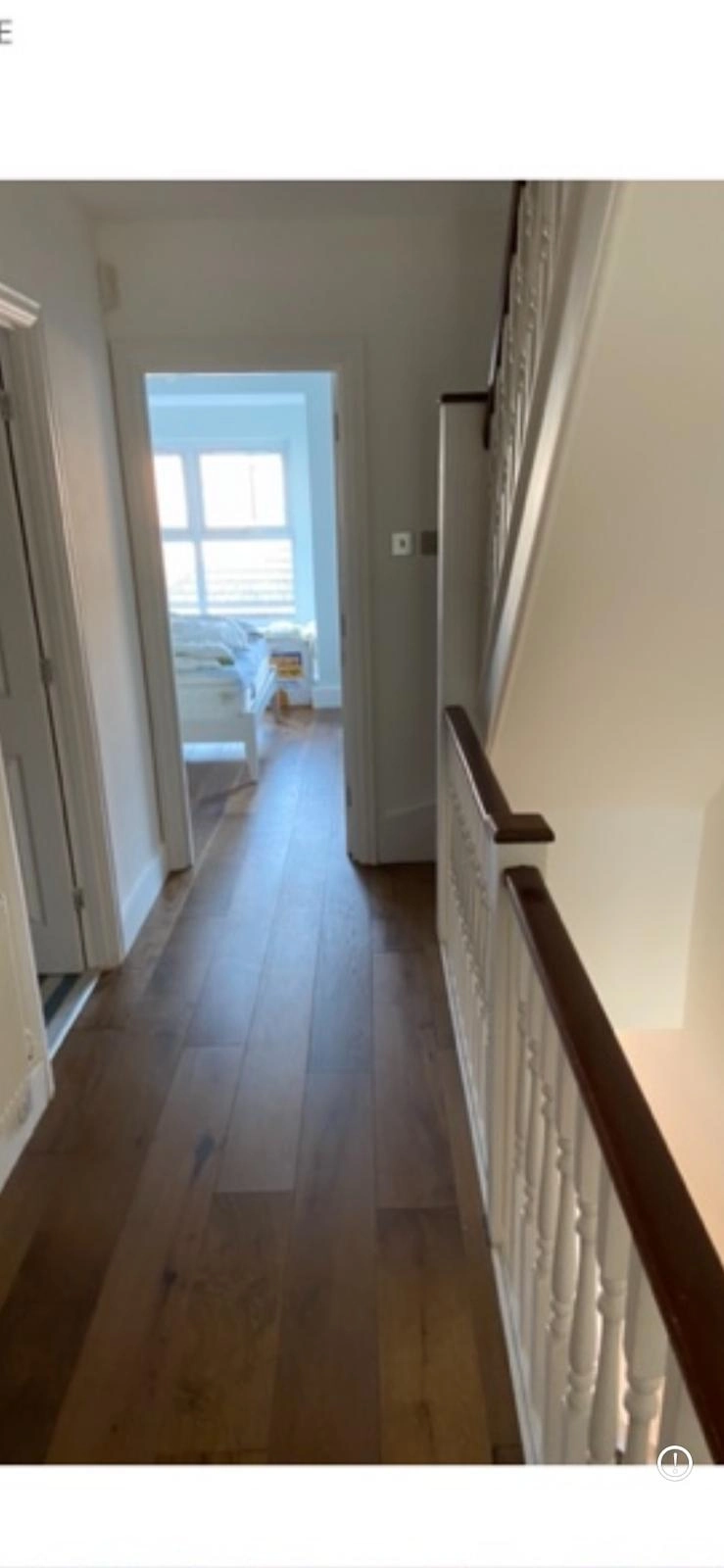 New oak wood flooring installation on an upstairs hallway landing featuring painted spindled balustrade and adjacent doorway