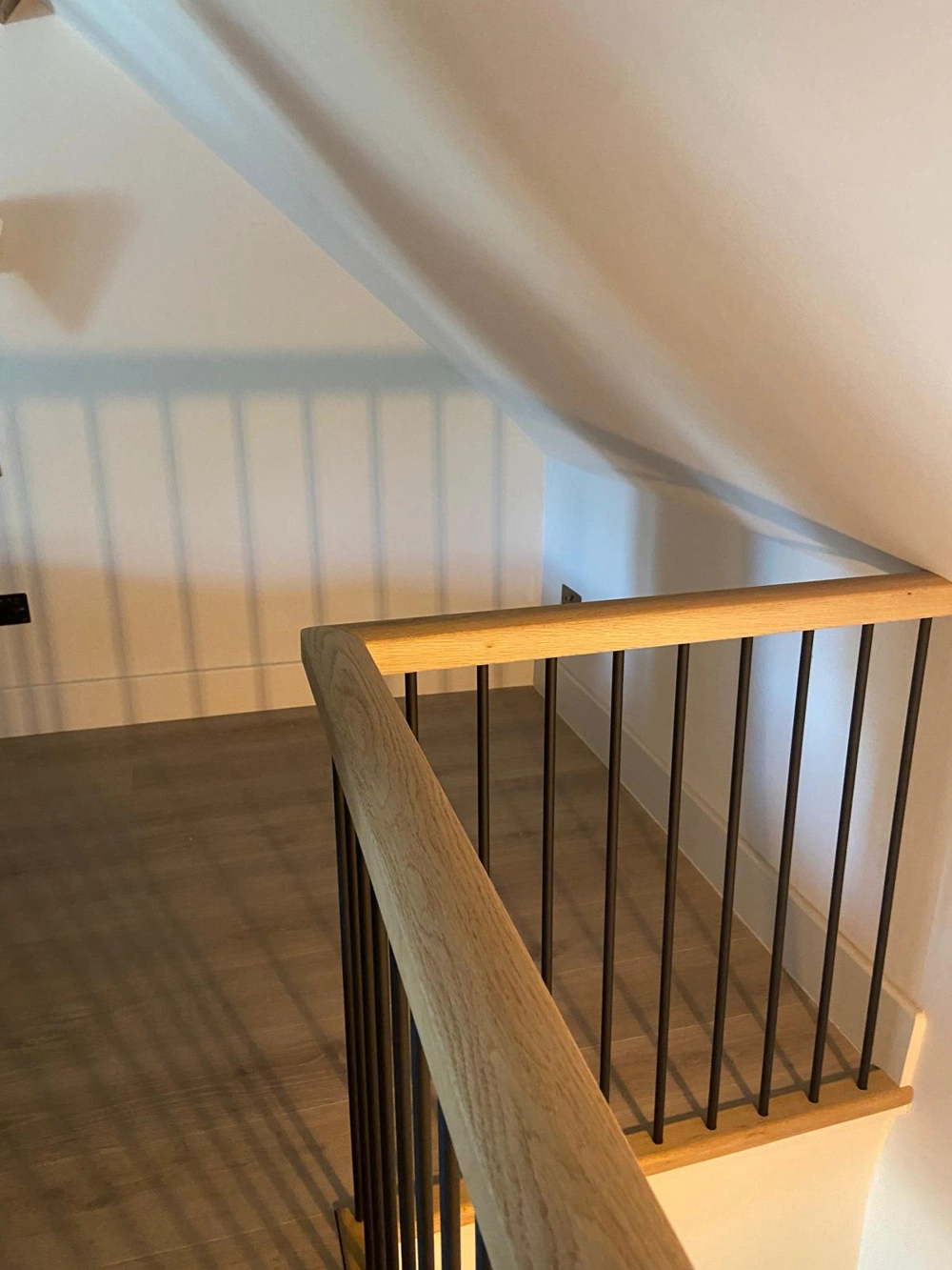 Carpentry – wooden handrail with black metal spindles on landing and oak flooring