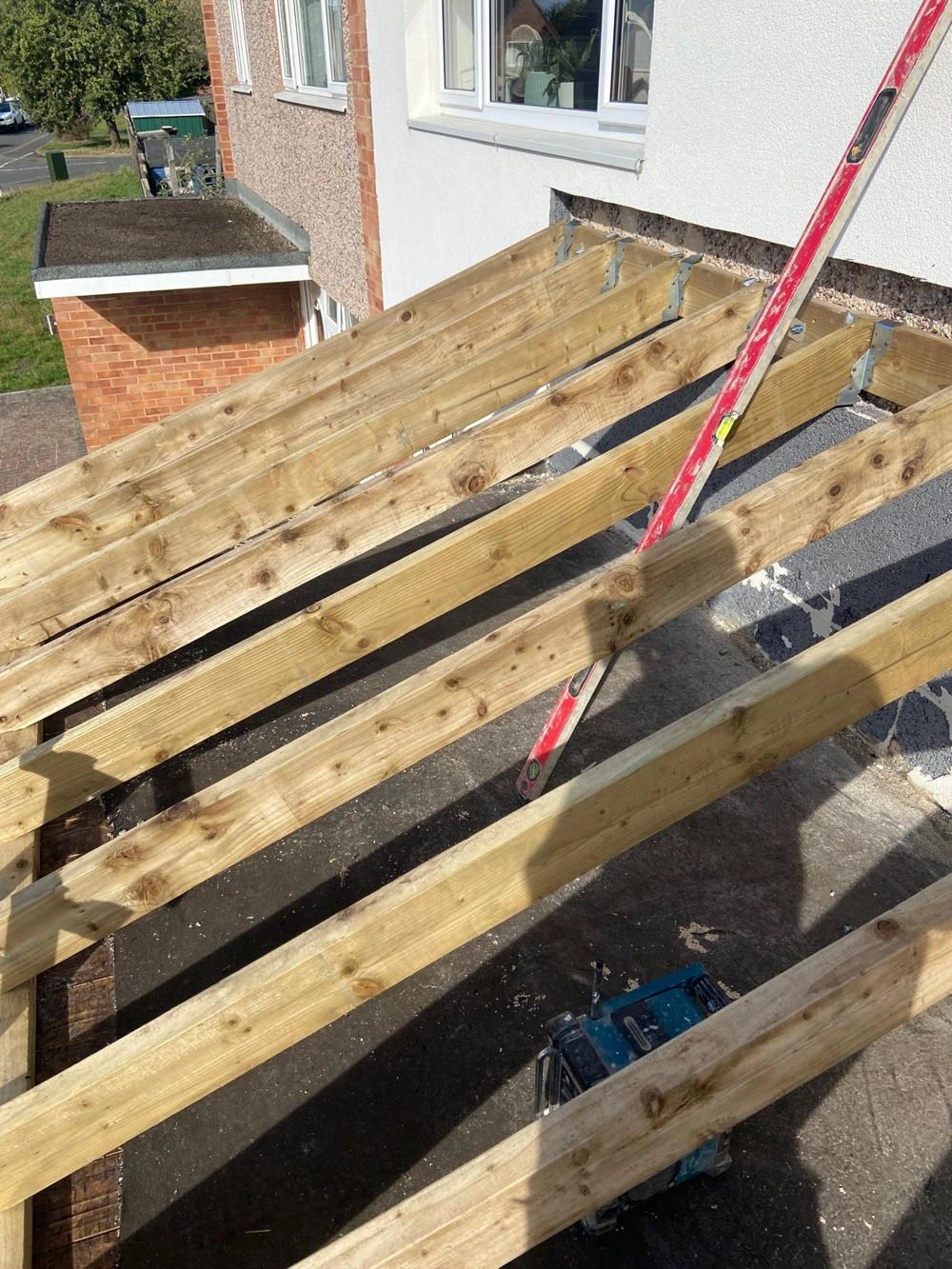 Wooden joists being installed on a flat extension roof frame before covering Roofing
