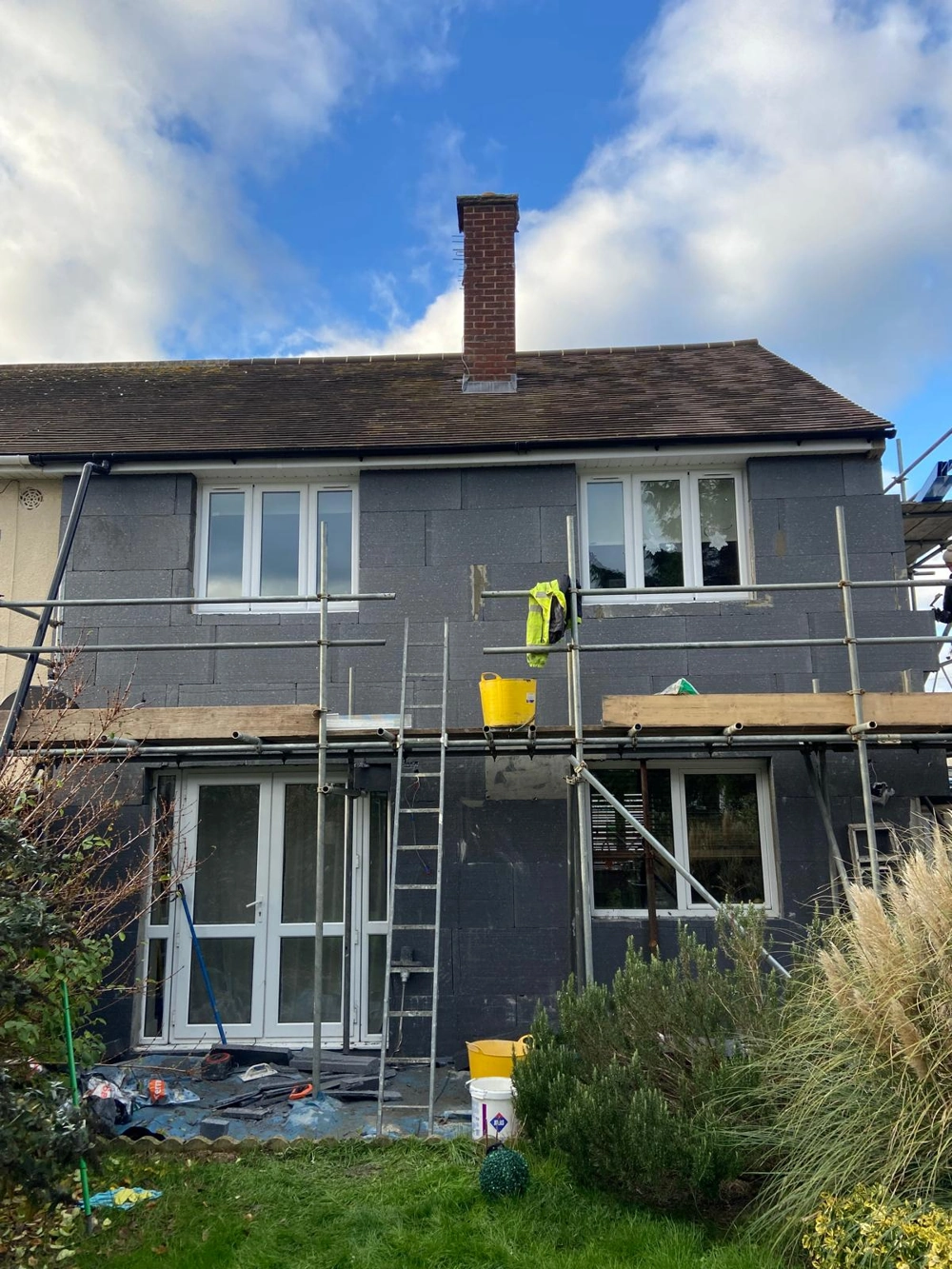 Two-storey house facade on scaffolding with grey insulation boards for Rendering