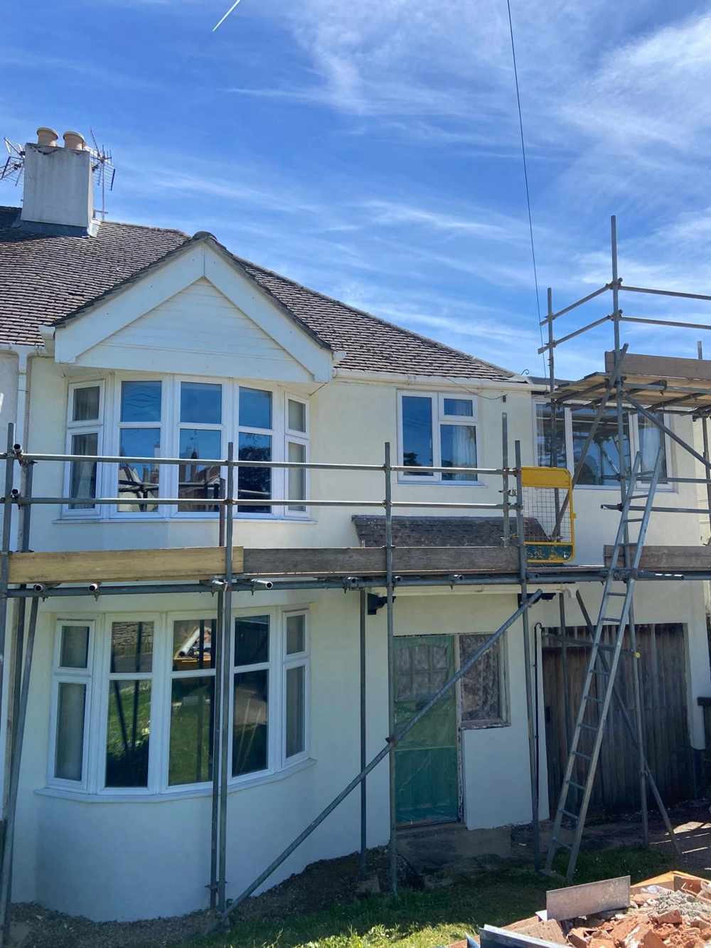 Two-storey house façade with scaffolding undergoing Rendering exterior renovation