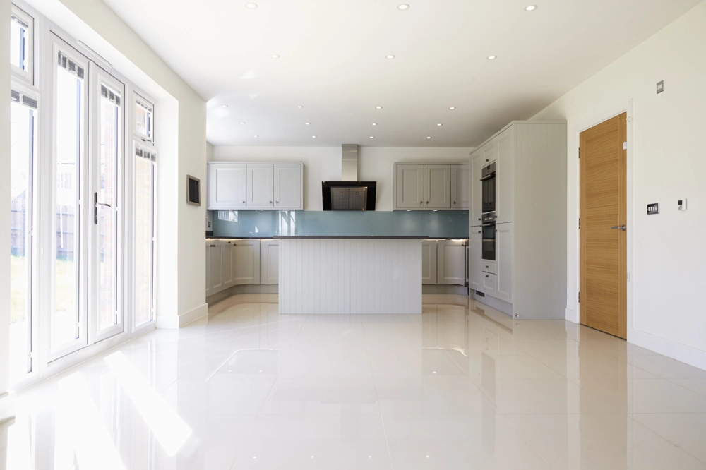 Spacious modern kitchen interior with central island, fitted cabinets on a glossy tiled floor and large glass doors – Kitchen Installation
