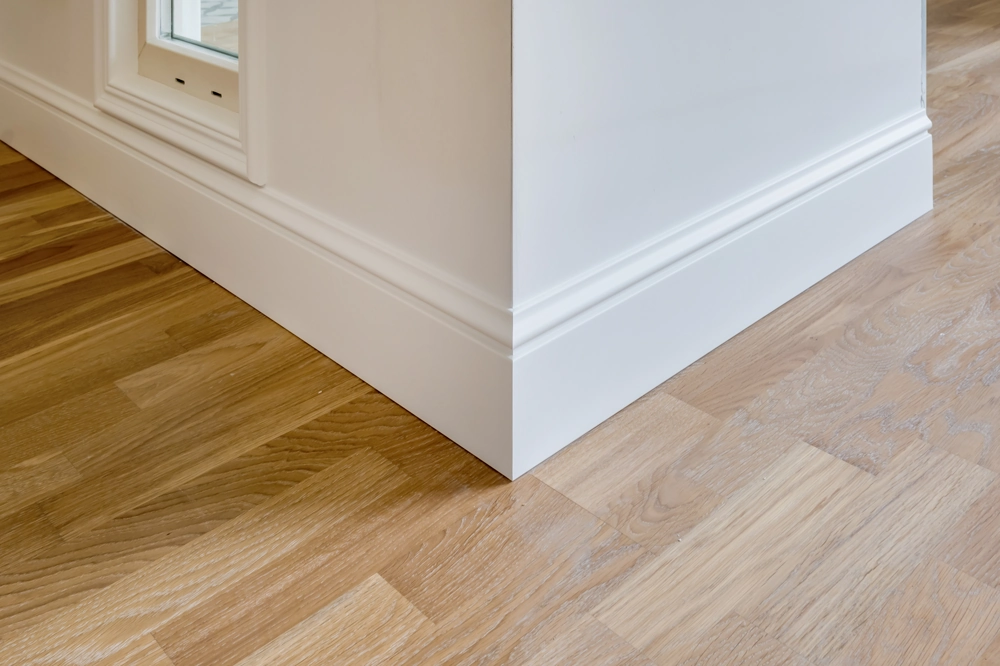 Interior corner showing oak wood flooring and white skirting board Wood Flooring