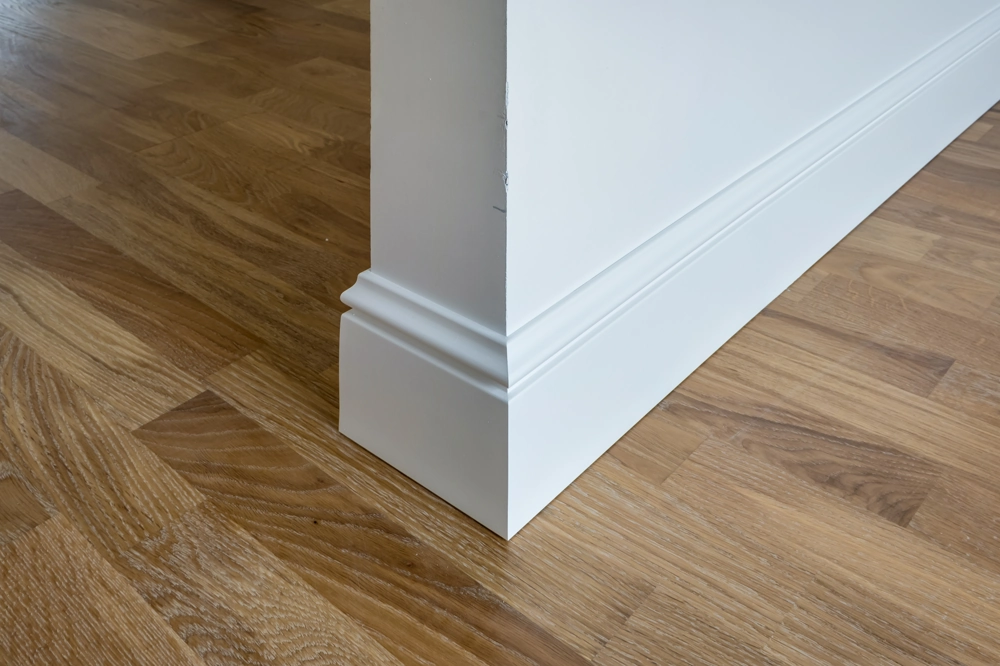 White skirting board fitted at the edge of oak wood flooring in an interior corner - Wood Flooring