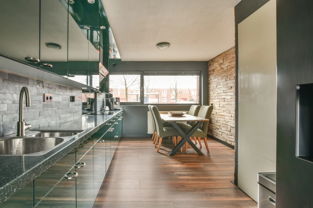 Modern galley kitchen with dark gloss cabinets, stone worktops, sink and dining area – Kitchen Installation