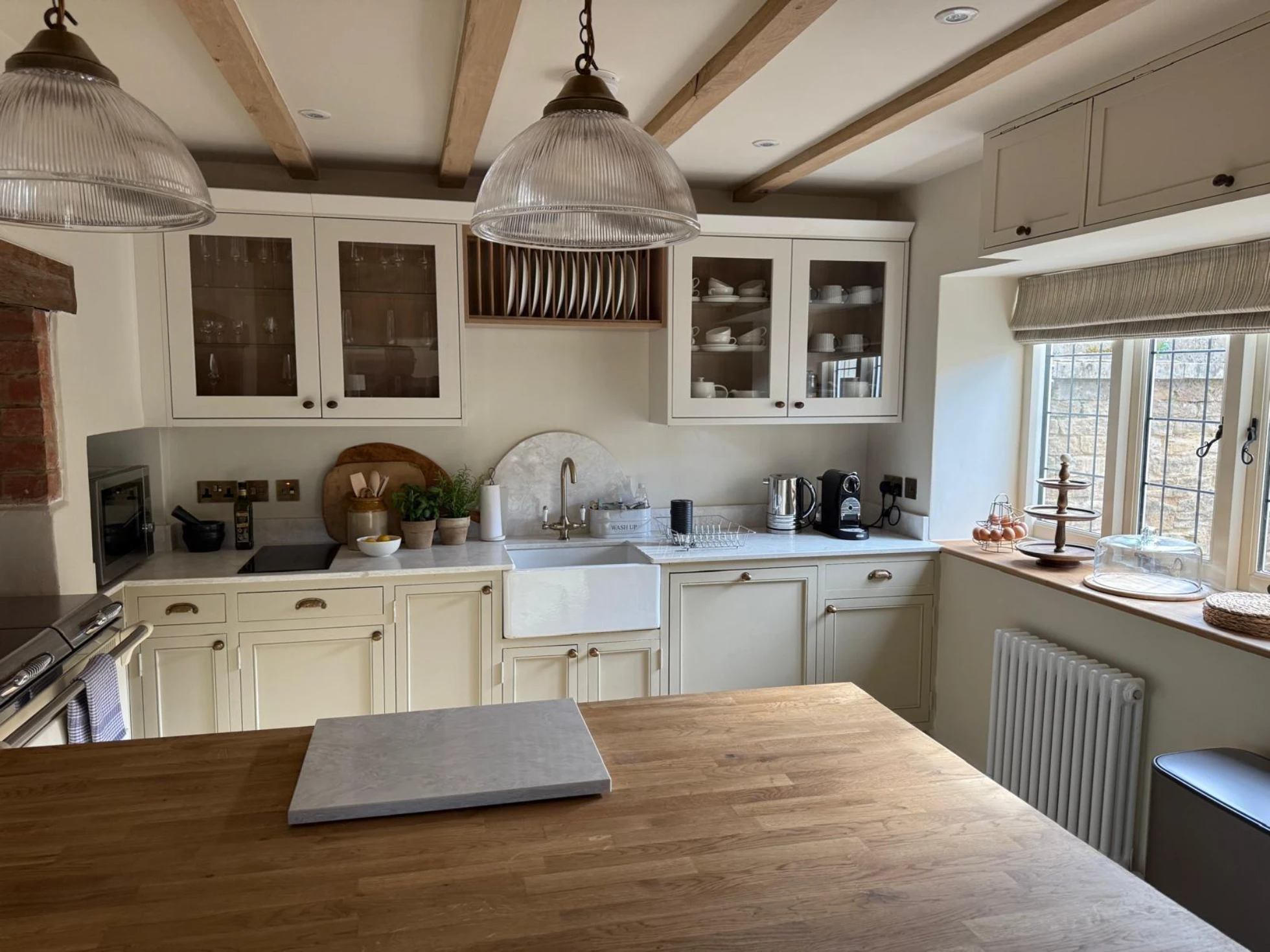 Spacious cream kitchen with wooden island, farmhouse sink, glass-front cabinets and pendant lighting showcasing Kitchen Installation