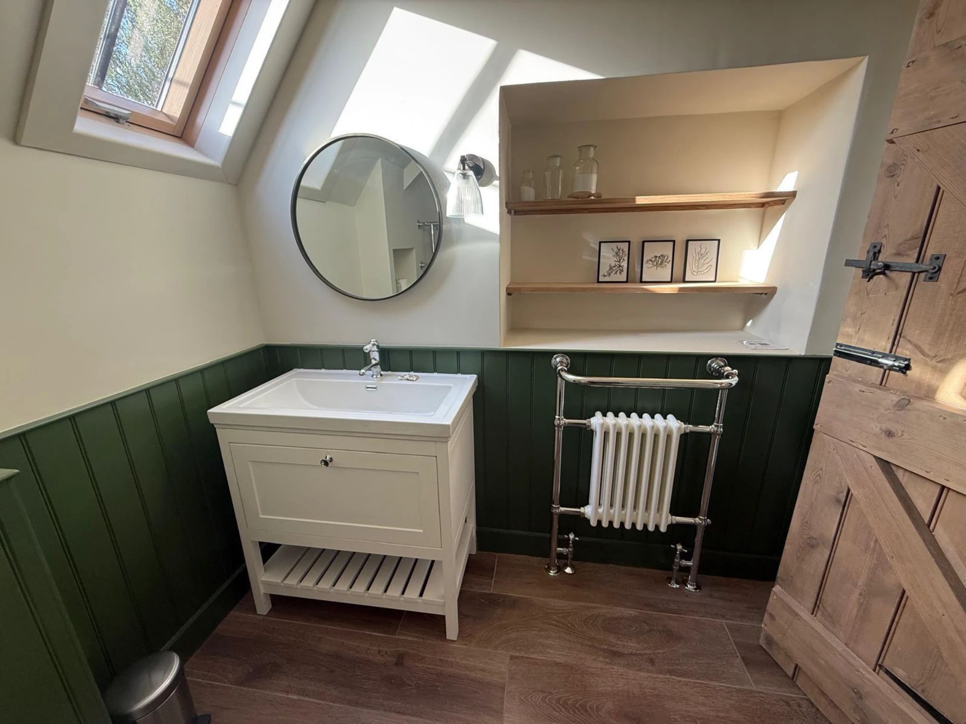 Bathroom Renovation: white vanity unit with sink, round mirror, chrome radiator towel rail and wooden shelves
