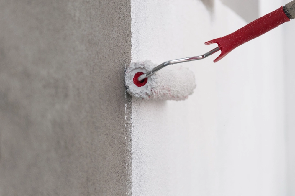 Interior Painting – paint roller applying white paint to a wall corner