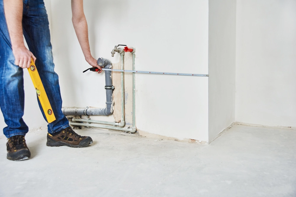 Technician measuring wall plumbing pipes with spirit level and tape, Plumbing and Heating