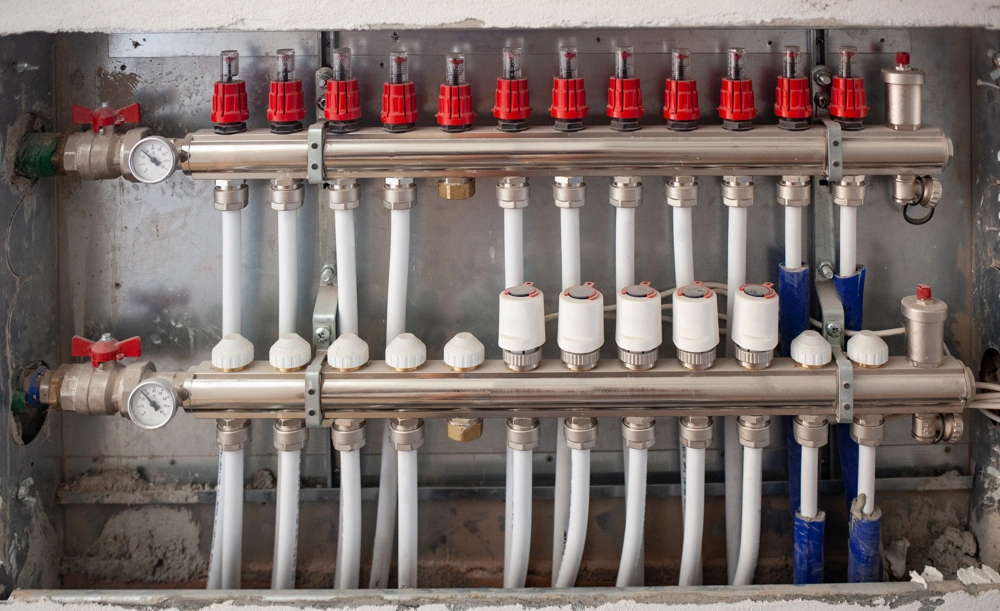 Stainless steel plumbing manifold with red and white valves and PEX pipes for Plumbing and Heating