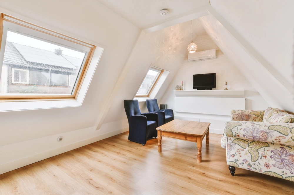 Loft Conversion living room with wooden floor, skylight windows, blue armchairs and wooden coffee table