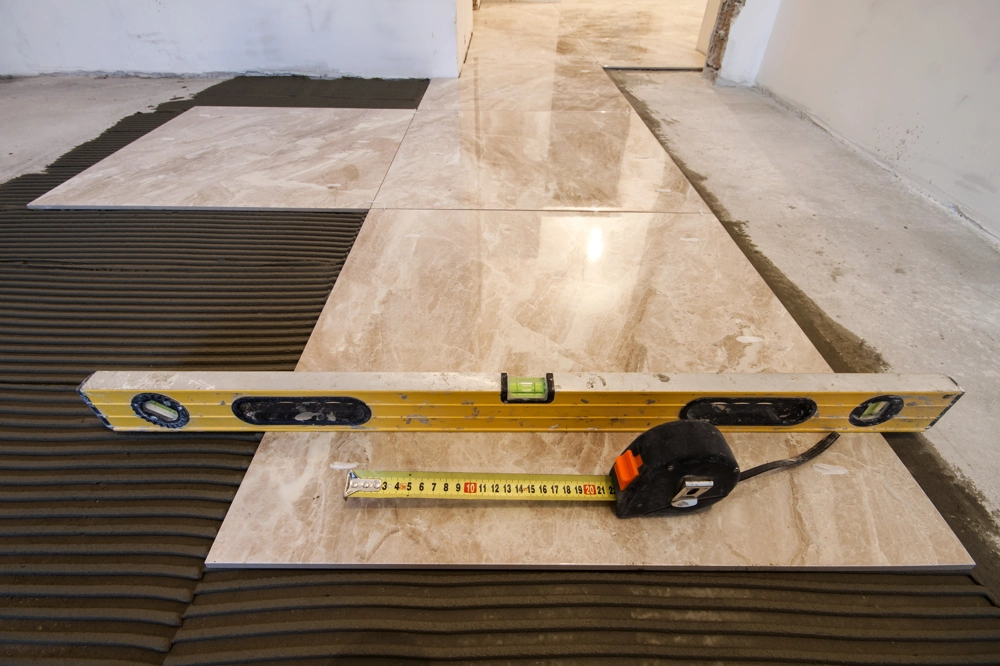 Spirit level and tape measure on partially installed floor tiles showing professional Floor Tiling work