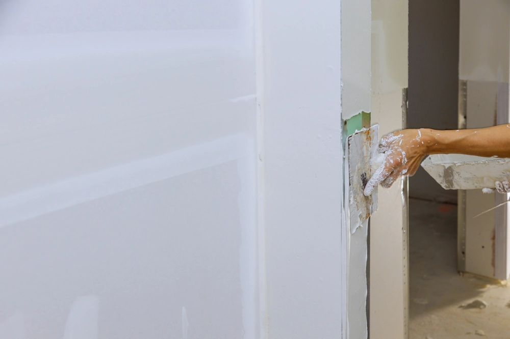 Worker smoothing plaster on internal wall with trowel - Plastering