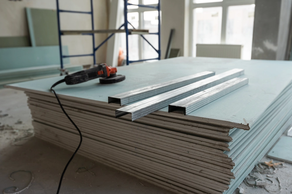 Stack of plasterboards and metal studs with angle grinder ready for Drylining